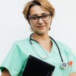 Confident female nurse with eyeglasses holding a tablet and stethoscope. Ideal for healthcare-related content.