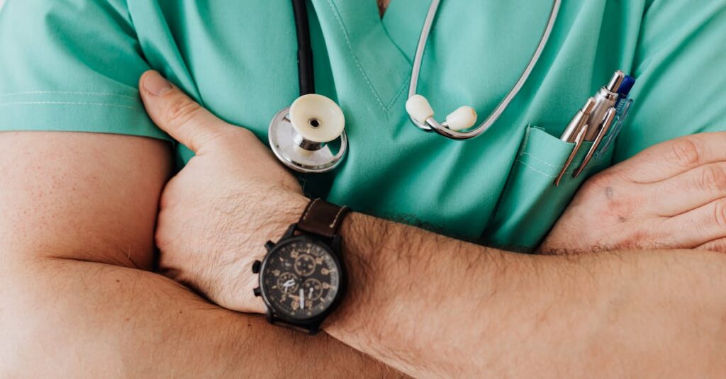 Close-up of a healthcare professional with arms crossed wearing medical scrubs and stethoscope.