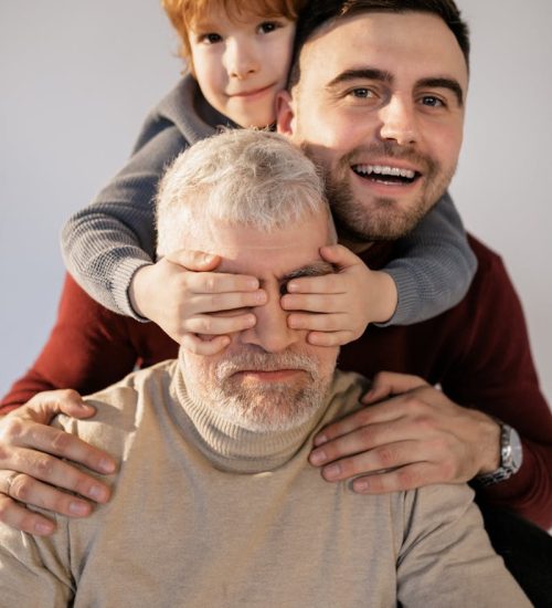 Joyful male family bonding, spanning three generations, with child, father, and grandfather.